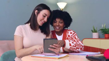 Mutlu Afrikalı Amerikalı ve Kafkasyalı öğrenciler birlikte oturup tablete bakıyorlar. Modern ortamlarda arkadaşlık, teknoloji ve öğrenme. Sosyal medyanın, eğitimin ve dijital bağlantının keyfini çıkarıyorlar.