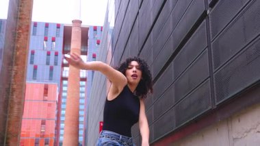 Afro-Amerikalı bir kadın şehir ortamında banklar arasında yaratıcı bir pozda dans ediyor. Günlük kıyafetler giyiyor ve denge, güç ve ifade gösteriyor. Hareket, sanat ve özgürlük kavramı. 