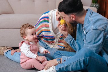 Gülümseyen ebeveynler küçük kızlarıyla birlikte evde eğleniyorlar. Sıcak ve samimi aile anı, ebeveynlik, çocukluk, aşk ve birliktelik için ideal.. 