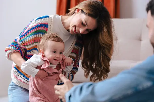 Anne ve baba, kızlarını halıya ilk adımlarını atarken cesaretlendiriyorlar. Evde sevgi, destek ve erken çocukluk gelişimiyle dolu iç açıcı bir aile anı.. 