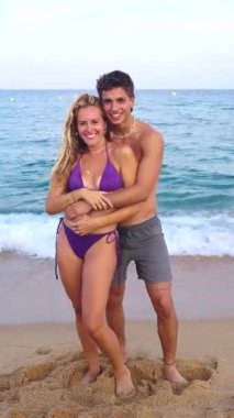 Gülümseyen etnik çeşitlilikte bir kadın ve tatilden zevk alan bir erkek. Güzel ve neşeli bir çift z nesli cep telefonlu fotoğraf için poz veriyor. Dikey