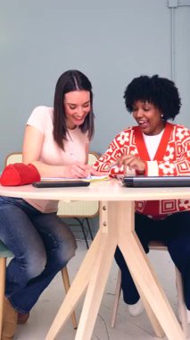 Afro-Amerikalı ve Kafkas öğrenciler evde birlikte çalışıyorlar, dizüstü bilgisayar kullanıyorlar ve not alıyorlar. Kırtasiye ve kitaplarla modern bir çalışma alanında ortak öğrenim, takım çalışması ve eğitim.