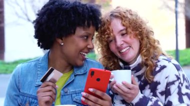 İki arkadaş palmiye ağaçlarının altında bir bankta oturmuş elinde kredi kartıyla bir alışveriş uygulamasını kontrol ediyor, açık hava zamanının, modern dijital alışverişin, arkadaşlığın, yazın arkadaşlığın tadını çıkarıyor. 