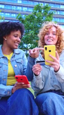 Çevrimiçi alışveriş yaparken ellerinde akıllı telefonlar ve bir kredi kartı olan Afro-Amerikan ve Kafkas arkadaşlarının dikey portresi, çeşitlilik ve kolaylığı ön plana çıkarıyor.. 