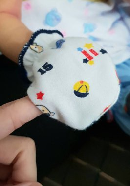 Yeni doğmuş bir bebeğin sağ eli, annesinin parmağını tutan bir eldiven.