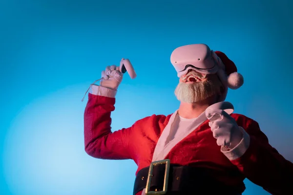 圣诞老人穿着Vr头盔装置设备观察现实的体验 年长的灰白头发胡子的圣诞老人在电子游戏中体验虚拟现实 — 图库照片
