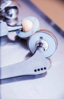 Bacak eklemlerinin nakli için pek çok parçayı ve eklemlerin değiştirilmesi için cerrahi işlemler için aletler metal bir yüzeye karşı yalan söyler.