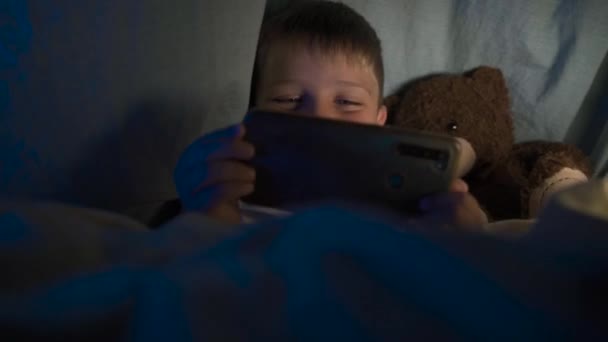 Ein Kleiner Junge Mit Einer Taschenlampe Unter Einer Decke Spielt — Stockvideo