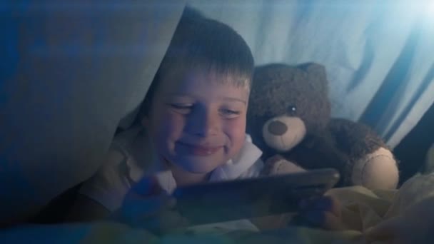 Ein Kleiner Junge Mit Einer Taschenlampe Unter Einer Decke Spielt — Stockvideo