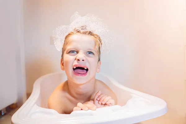 funny little boy five year old sitting in the bathtub