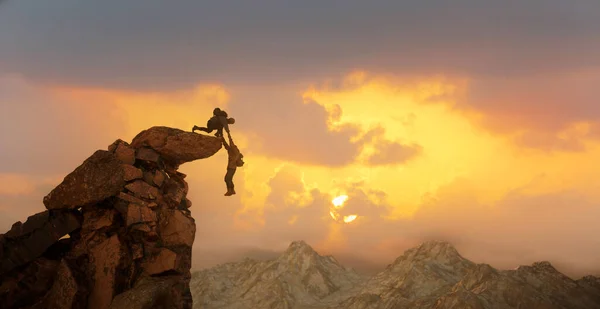 A hiker climber helps a friend not to fall from the cliff to reach the mountain top render 3d