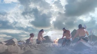 Kamp ateşinin yanındaki tarih öncesi mağara adamları.