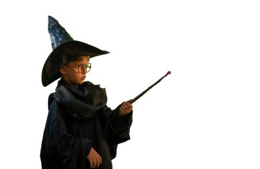 Beyaz arka planda Cadılar Bayramı kostümü giymiş sihirli değneği olan büyücü bir çocuk. 