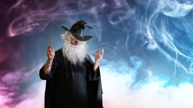Büyücü yaşlı adam sihirli değnekle büyü yapıyor. 