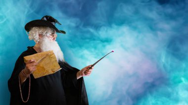 Büyücü yaşlı adam sihirli değnekle büyü yapıyor. 