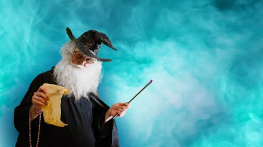 Büyücü yaşlı adam sihirli değnekle büyü yapıyor. 