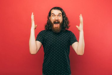 Pembe arka planda el kol hareketi yapan sakallı adamın fotoğrafı..