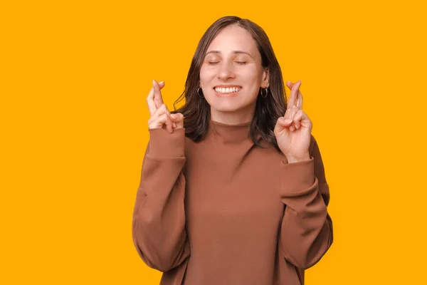 喜びの女性の肖像画でパーカーの交差指と願い何かのために黄色の背景 — ストック写真