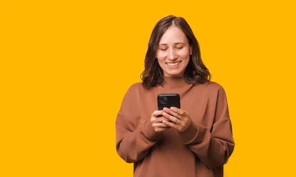 Photo Happy Woman Hoodie Using Smartphone Yellow Background — Stock Photo, Image
