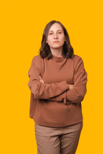 Pionowe Zdjęcie Młodej Poważnej Kobiety Stojącej Skrzyżowanymi Ramionami Żółtym Tle — Zdjęcie stockowe