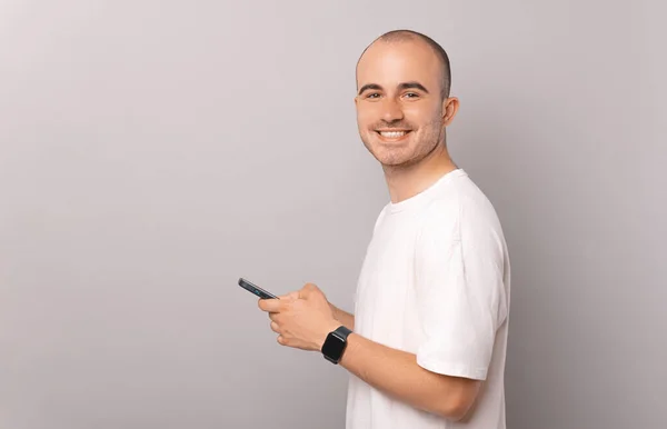 Portrait Young Man Holding Smartphone Smiling Looking Camera Grey Backdrop — Stock Photo, Image
