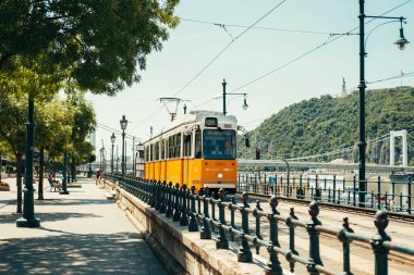 Macaristan, Budapeşte. 15 Haziran 2022. Budapeşte 'de Tuna Nehri kıyısındaki sarı tramvay güneşli bir yaz gününde.