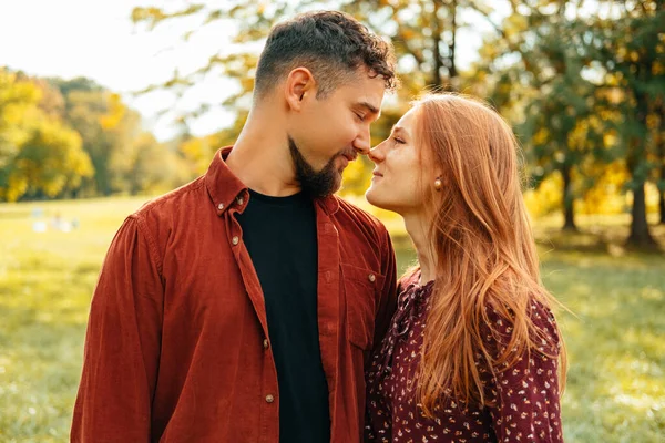 お互いに恋に冷たい若いカップルが鼻や笑顔に触れている 緑の公園の屋外写真 — ストック写真