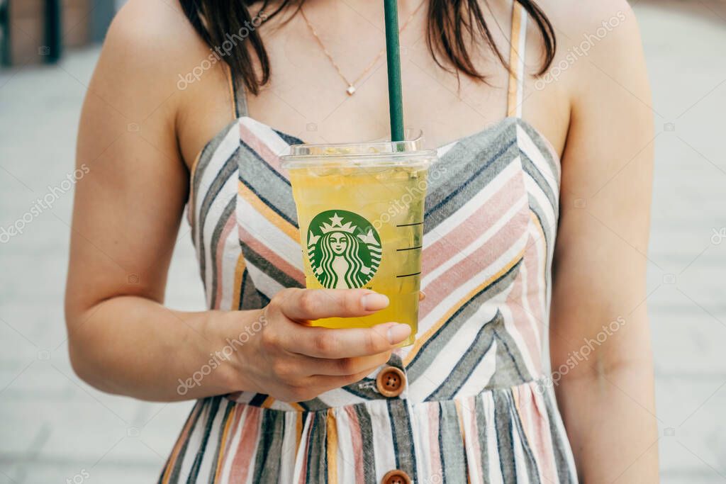 Hungary, Budapest. 16 JUNE 2022. Faceless photo of a young woman holding a fresh lemonade made by Starbucks on a sunny day.