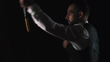 Takım elbiseli bir adamın siyah arka planda nunchaku egzersizi yaptığı görüntüleri kapat..