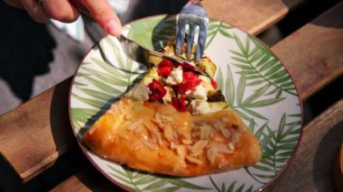 Dışarıdaki kafede sebzeli tart yiyen kadının görüntülerini kapatın..