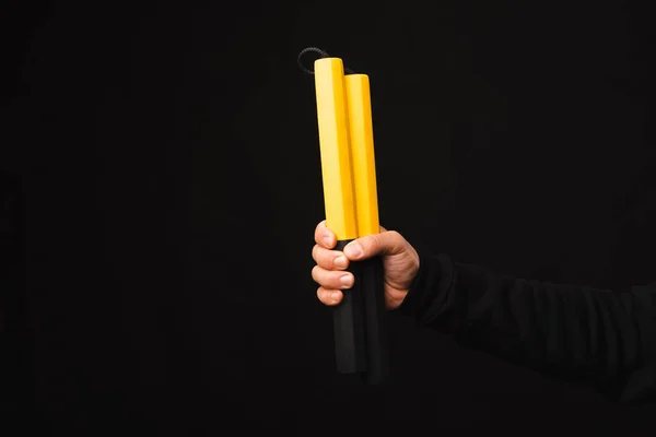 stock image Close up photo of male string hands holding yellow nunchacku sticks.