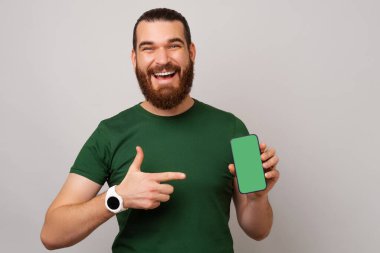 Elinde tuttuğu boş telefon ekranına yeşil tişört giyen heyecanlı genç adam..