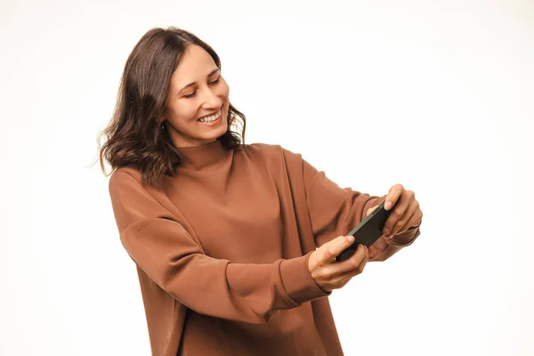 Neşeli Genç Esmer Kadın Beyaz Bir Stüdyoda Cep Telefonuyla Oynuyor — Stok fotoğraf