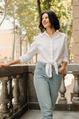 Hayalperest genç kadın yazın balkonda neşeli bir şekilde gülümsüyor..