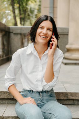 Sokakta merdivenlerde otururken telefonla konuşan bir kadının portresini kapat..