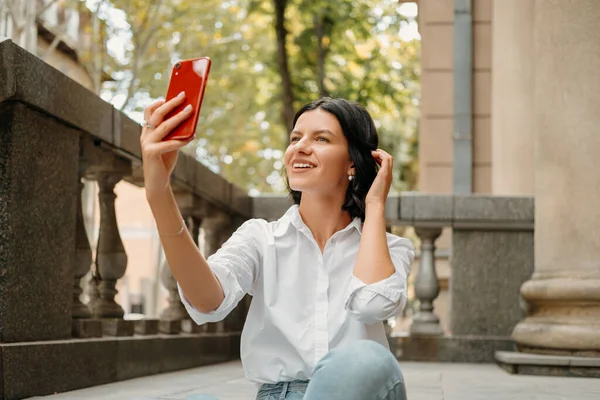 Mulher Sorridente Está Tomando Uma Selfie Com Seu Telefone Vermelho — Fotografia de Stock