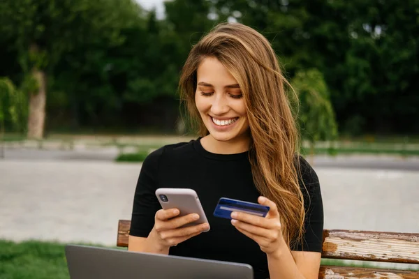 Mulher Sorridente Larga Está Usando Seu Telefone Cartão Crédito Enquanto — Fotografia de Stock