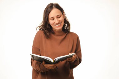 Heyecanlı kadın elinde tutarken bir günlüğe ya da kitaba bakıyor ve okuyor. Stüdyo çekimi beyaz arkaplan üzerinde.