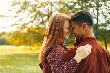 Happy young couple are laughing together while spending time in a park. Some copy space aside. clipart