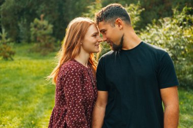 Birbirine aşık çiftler ayakta durup burunlarına dokunuyor ve gün ışığında birbirlerine gülümsüyorlar..