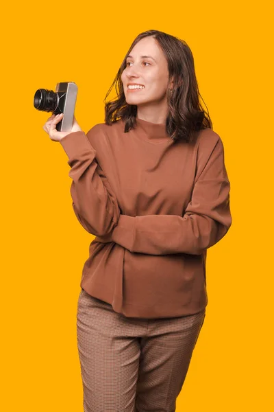 Pionowe Ujęcie Młodej Kobiety Trzymającej Zabytkową Kamerę Spoglądającej Żółte Tło — Zdjęcie stockowe