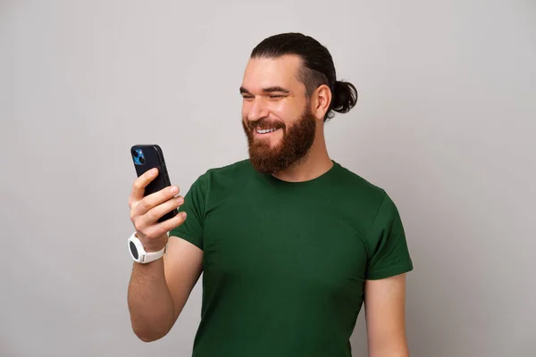 Happy Bearded Man Wearing Green Holding His Phone Looking While — Stock Photo, Image