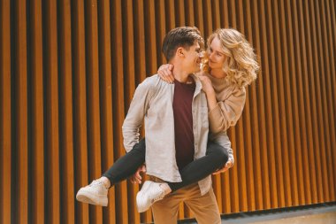 Aşık genç adam sokakta domuzcuğunu sırtında tutuyor..