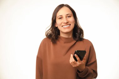 Geniş, gülümseyen bir kadının modern bir telefonu beyaz arka planda tutan portresini yakından çek..