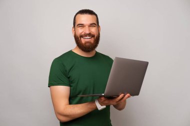 Yeşil giyen yakışıklı güçlü adam bilgisayarını açıp bir şeyler yazıyor..