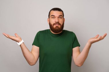 Kafası karışmış genç sakallı adam omuz silkiyor çünkü ne cevap vereceğini bilmiyor..