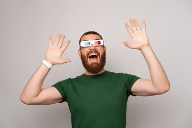 3D gözlük takan heyecanlı sakallı adam açık gri arka planda film efektlerine şaşırdı..