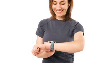 Spor kıyafetleri giyen genç bir kadın kulaklık takarken yeni ukalalığına bakıyor..