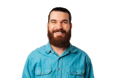 Portrait of a wide smiling young bearded man wearing blue jeans shirt. Studio shot over white background.