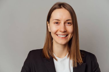 Simple portrait of a handsome wide smiling young woman over grey background.